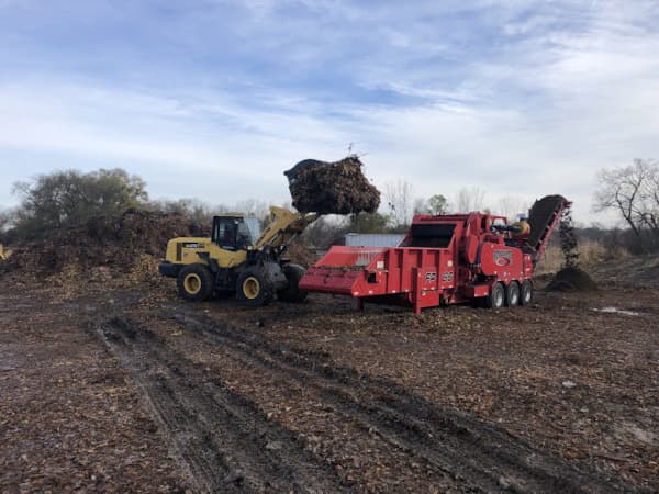 Loading tree into huge tub grinder machine